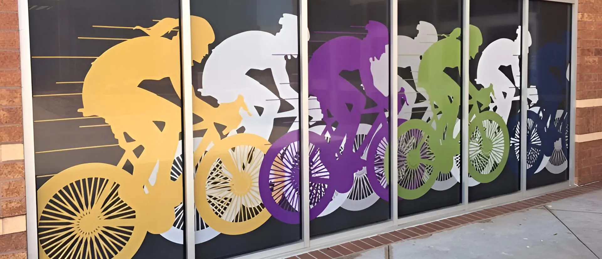 A wall with four different colored bicycles on it.